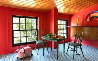 A playroom with bright red walls and ceiling, blue floor and green table and chairs.