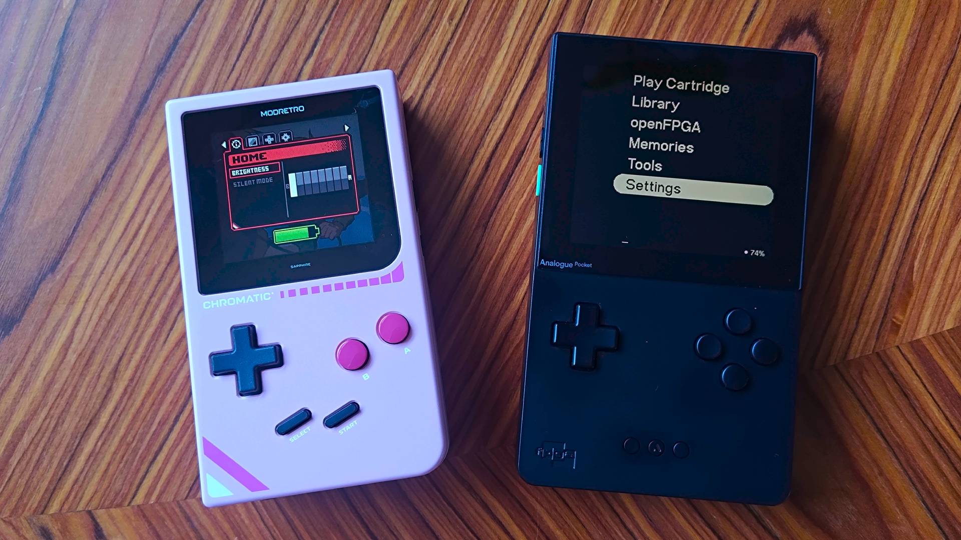 Analogue Pocket on right and Modretro Chromatic on left sitting on woodgrain table with respective menus displayed.
