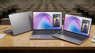 Three XPS 13 laptops on a wooden desk in a lecture hall, two open with colorful screens, one closed with "XPS" on the back.