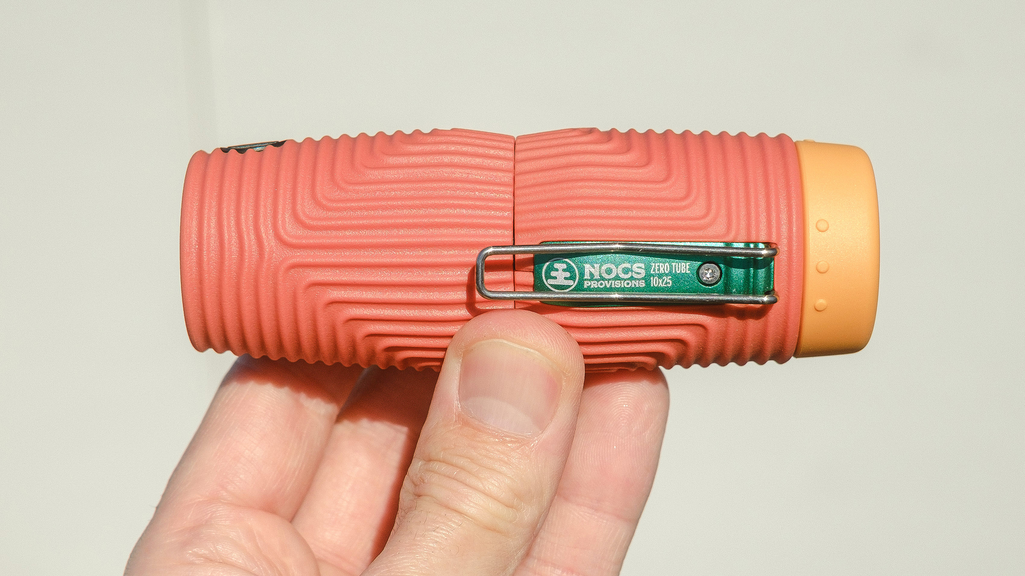 Nocs Zero Tube rugged monocular in orange shown close-up in a user's hand
