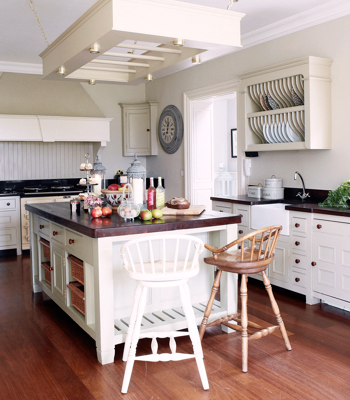 An example of portable kitchen island ideas showing a white island with mis-matched wooden bar stools