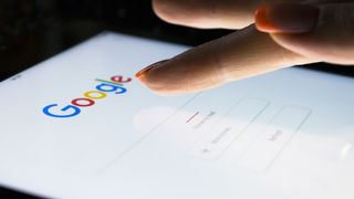 A person tapping the Search bar of google.com, demonstrating how to remove contact details from google search