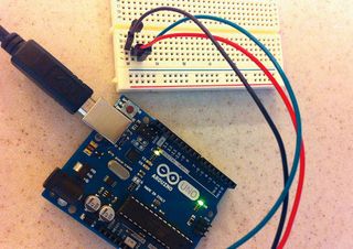 A typical Arduino set-up, consisting of cables, wires, pins, sensors and a USB laptop connection