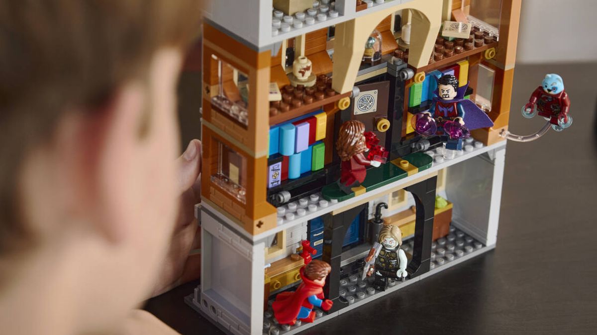 A boy looks over at the rear of the Lego What If Sanctum Sanctorum, with minifigures posed in battle with each other