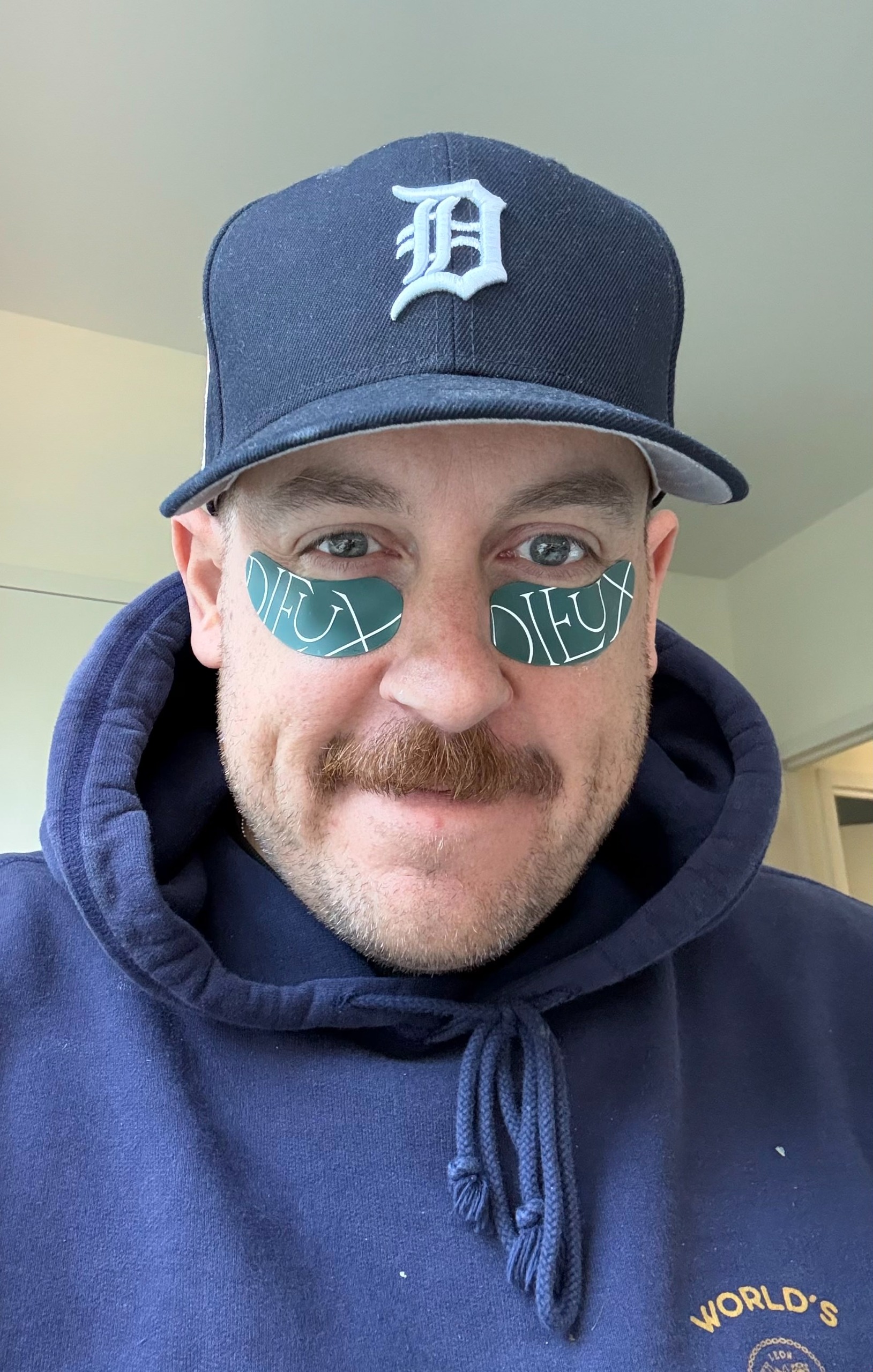 a white man with a mustache in a blue hoodie and blue hat