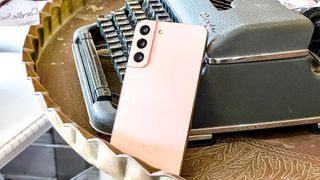 galaxy s22 plus in pink leaning against antique typewriter
