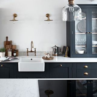kitchen with black cabinets and gold kitchen fixtures with white wall