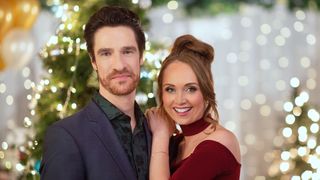 Ben Mehl, Amber Marshall pose in front of a tree in My Christmas Guide