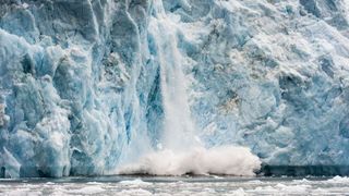 Ice calving from the fracture zone of a glacier crashes into the ocean in Greenland. Melting of such glacial ice is leading to the warping of Earth's crust.