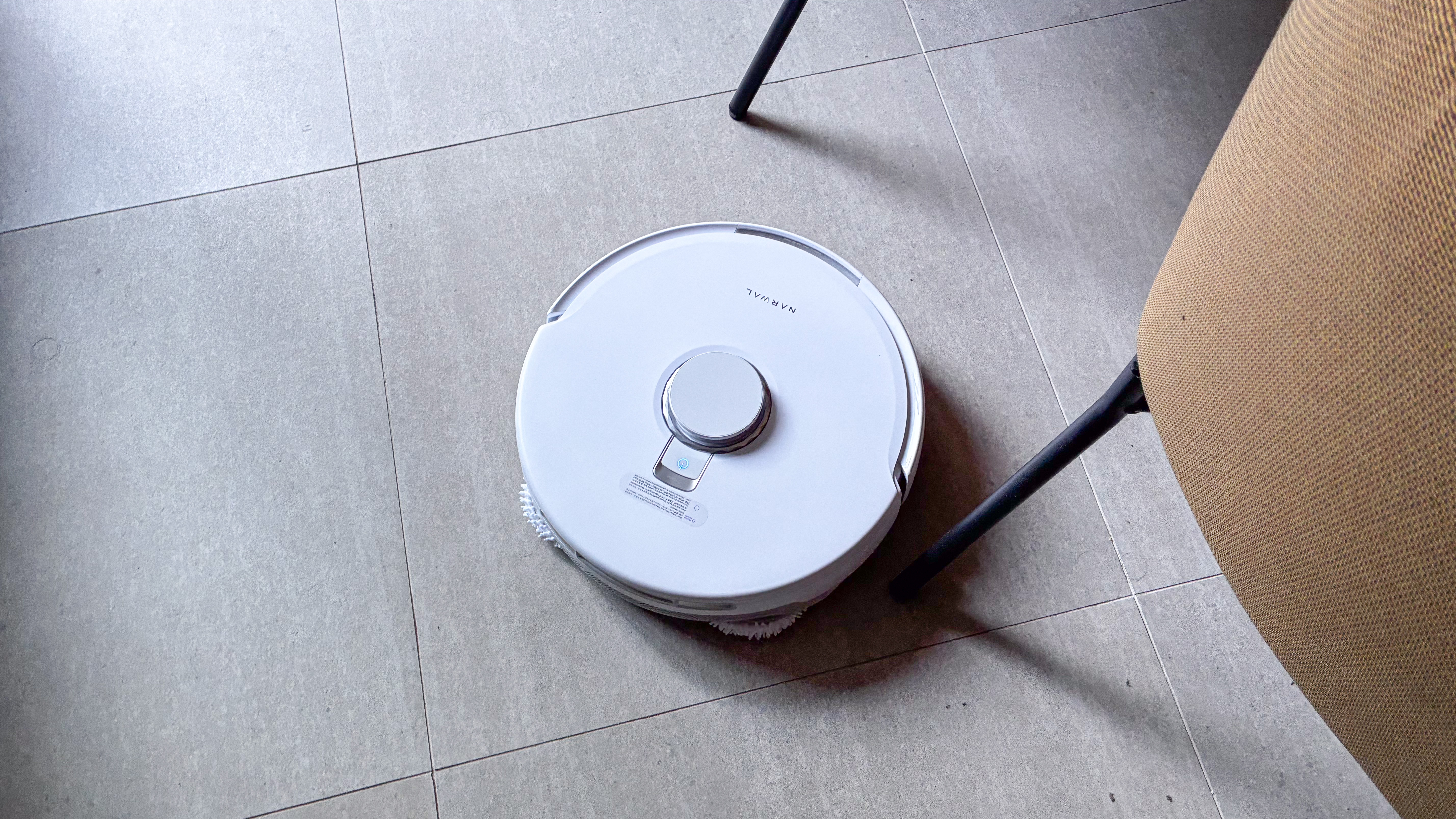 Narwal Freo Z10 cleaning around a chair leg on a tiled floor