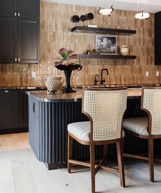 kitchen with dark charcoal cabinets, beige gloss wall tiles, and rattan bar stools around the island