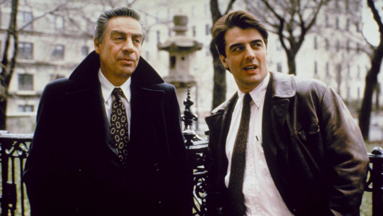 Chris Noth wears a leather jacket over a suit and tie while playing a detective along with another male cop in an nyc park in &#039;Law &amp;amp; Order&#039;