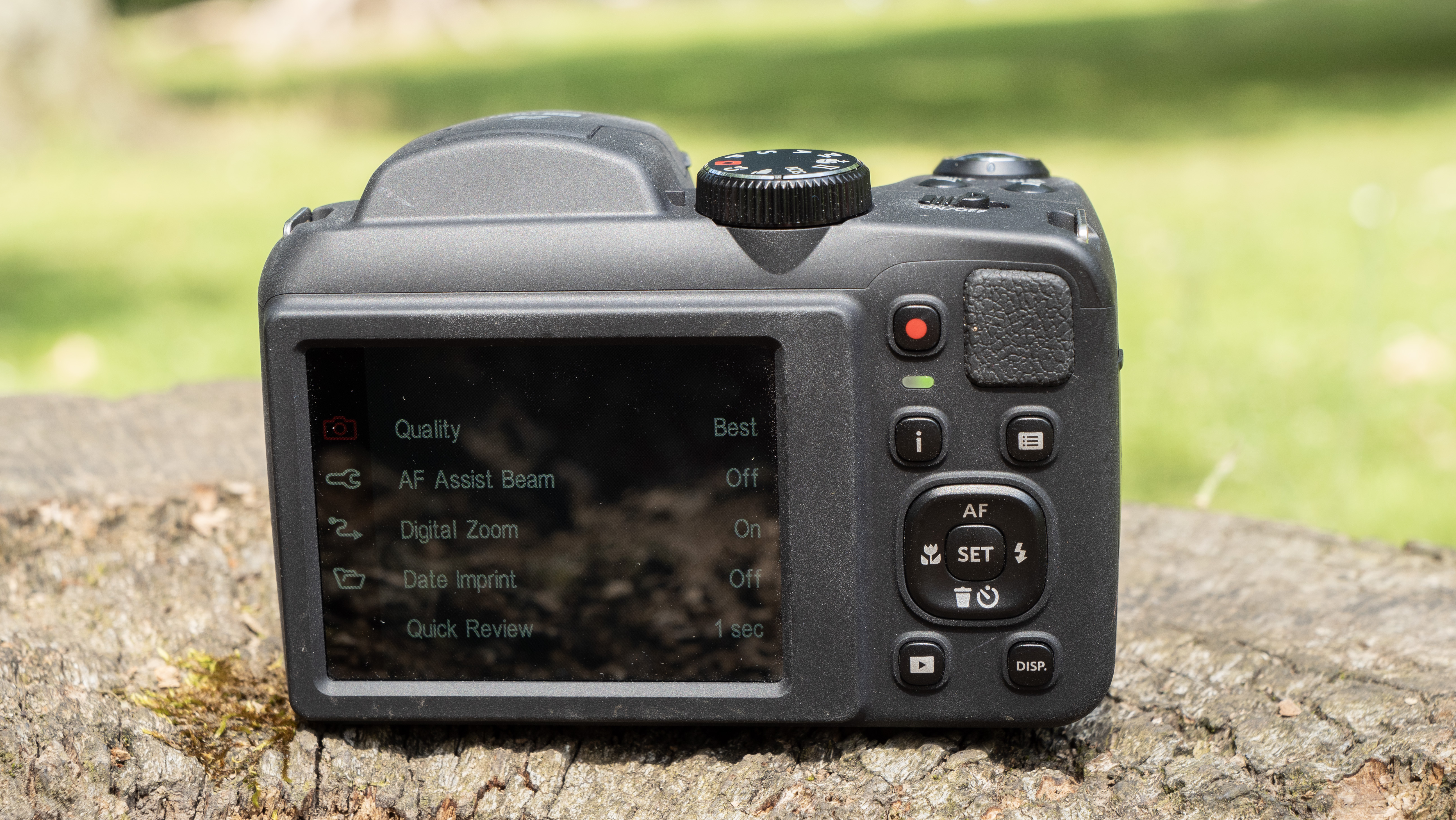 Kodak PixPro AZ255 digital camera in black on a stone surface in front of a green background outside