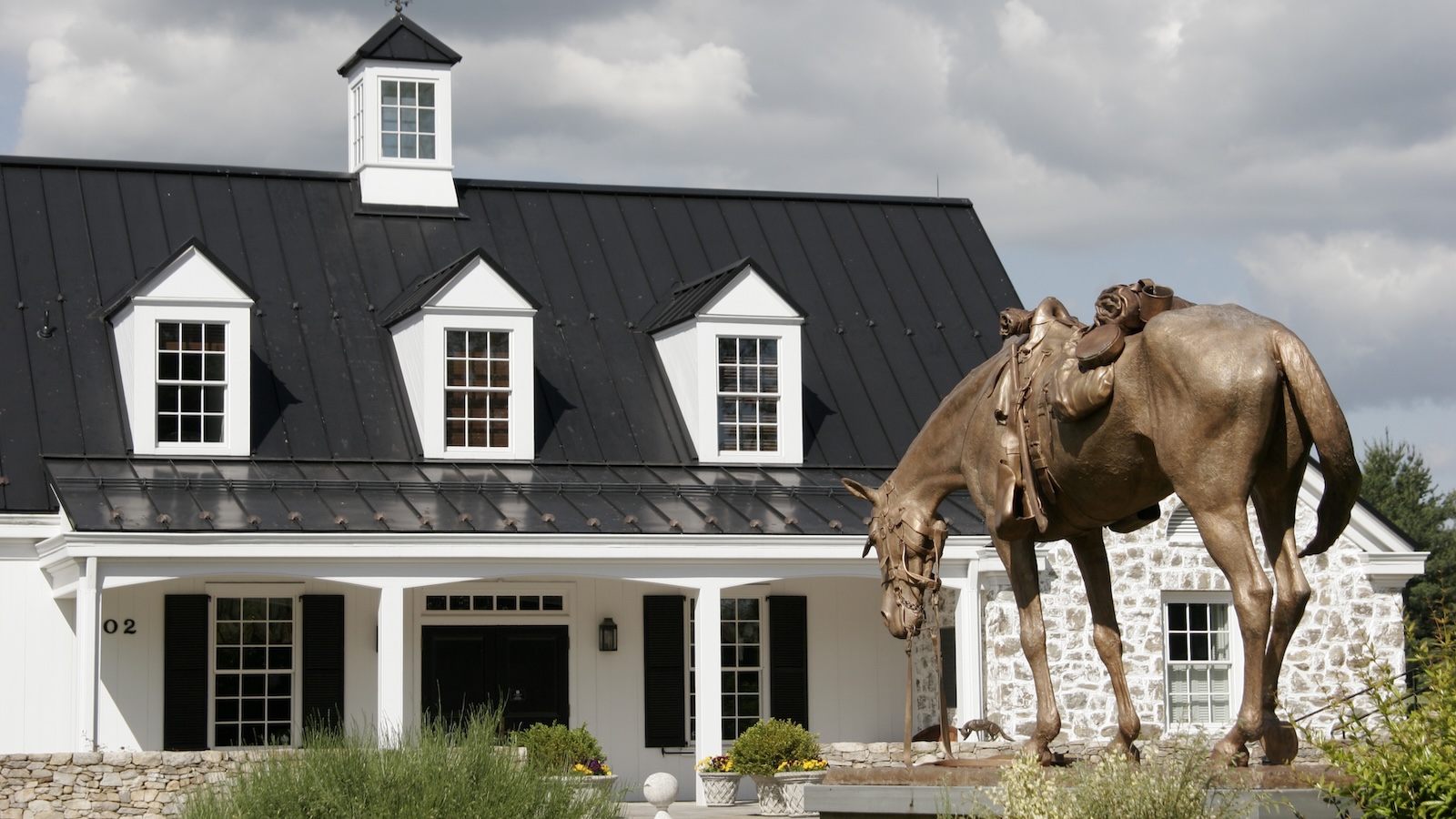 The white barn-like exterior of the National Sporting Library &amp;amp; Museum in Middleburg, with a statue of a riderless, saddled horse out front.