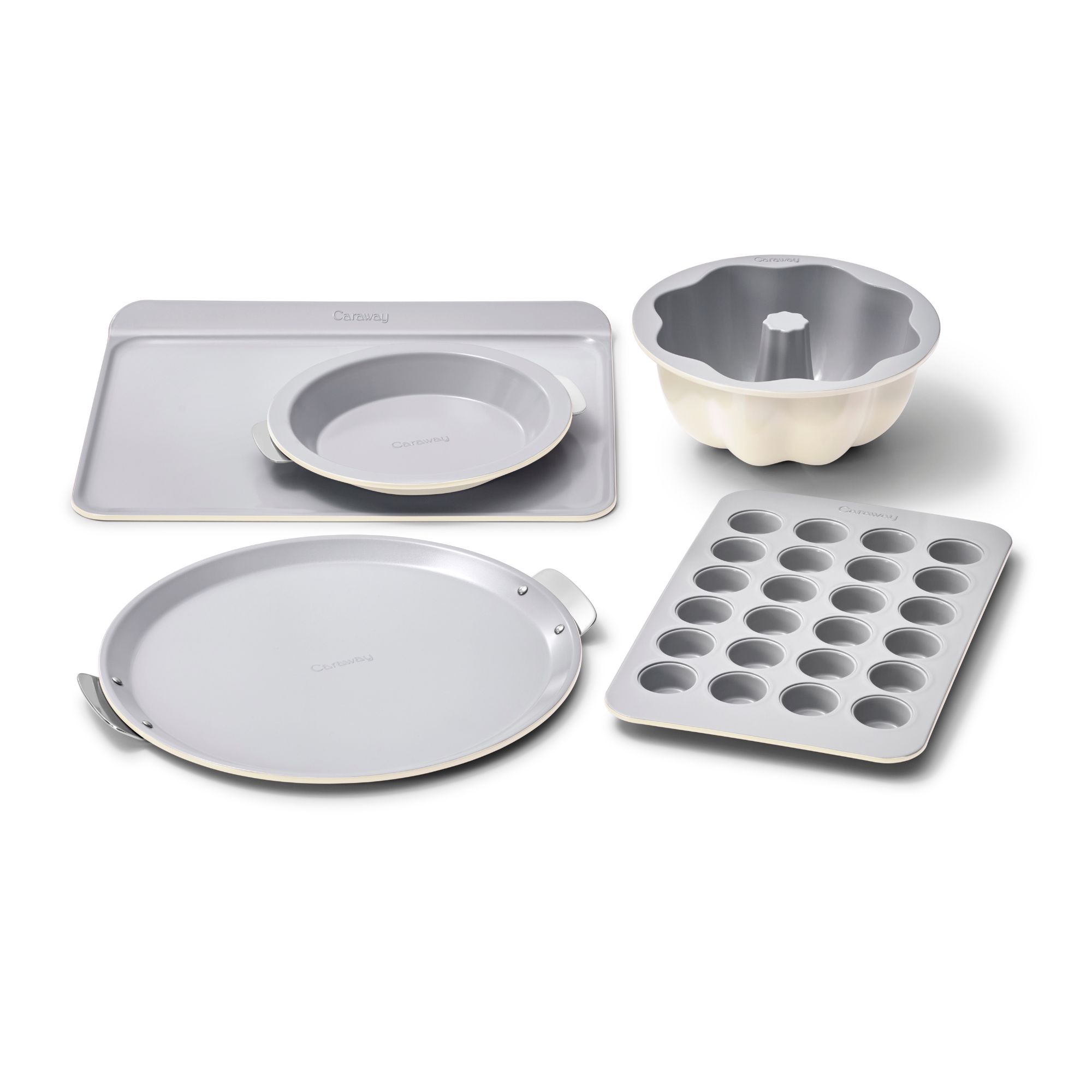 The complete caraway bakeware+ collection including a muffin tin, a baking sheet, a pie dish, a pizza tray, and a Bundt tin on a white background.