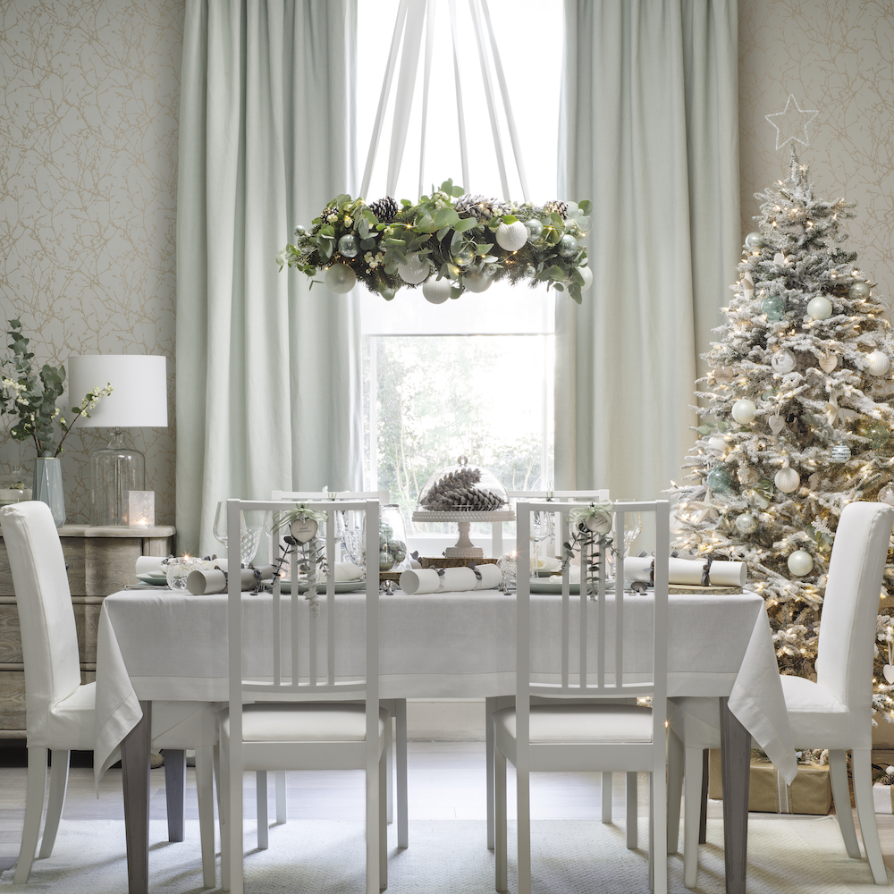 Christmas dining room in whites and pale green with wreath hanging over table
