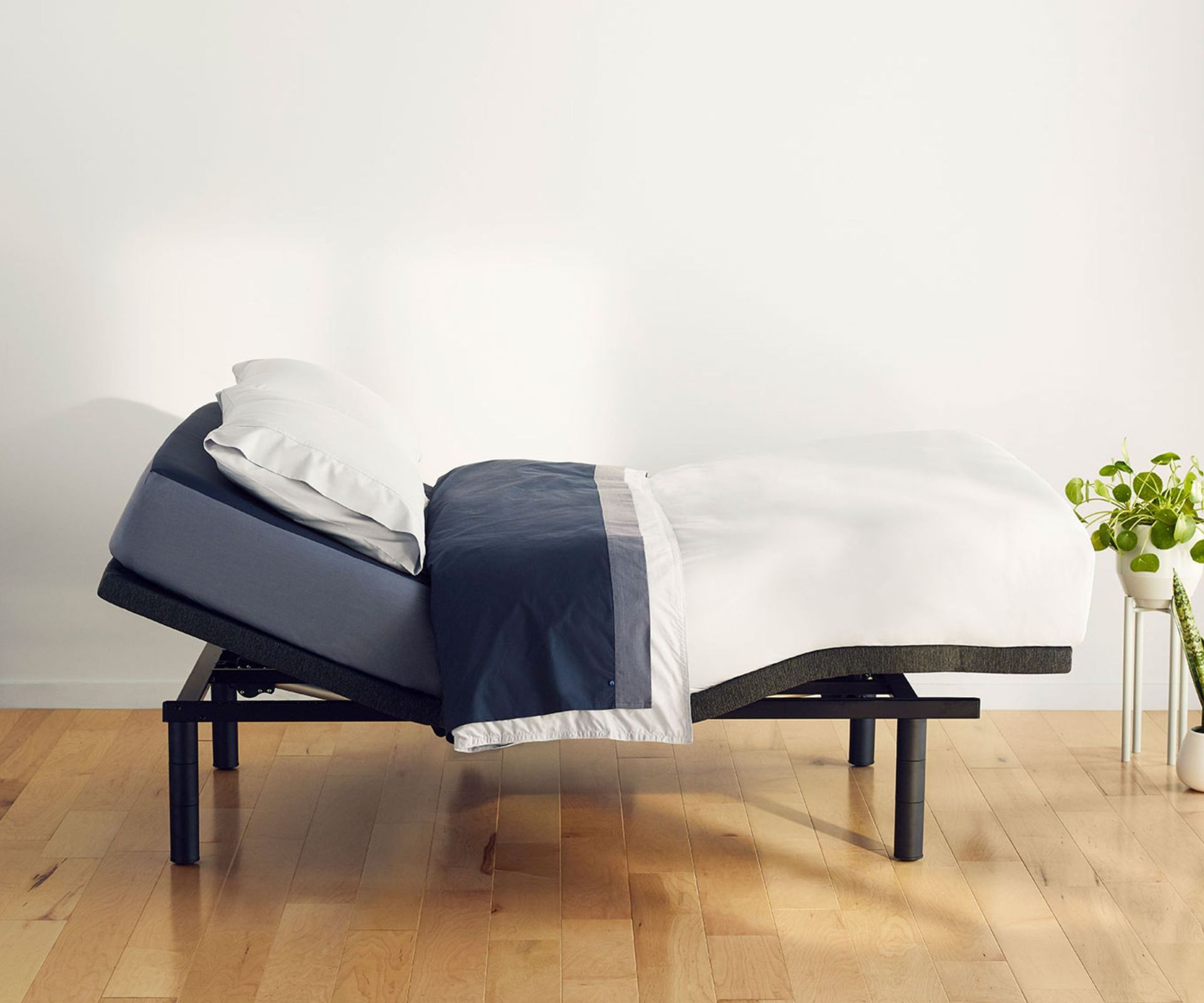 Side view of white and navy bedding on the Casper Adjustable Base.