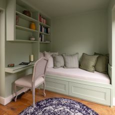 built in day bed with wall storage painted in green, desk area, chair, cushions