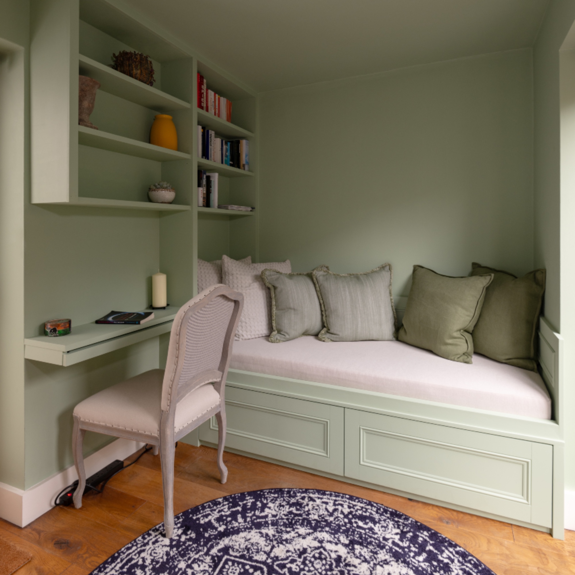 built in day bed with wall storage painted in green, desk area, chair, cushions