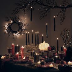 A gothic Halloween table set up with black candles and an LED pumpkin from Lights4Fun.