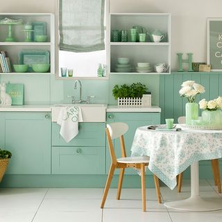 Green kitchen units and pine table and chairs