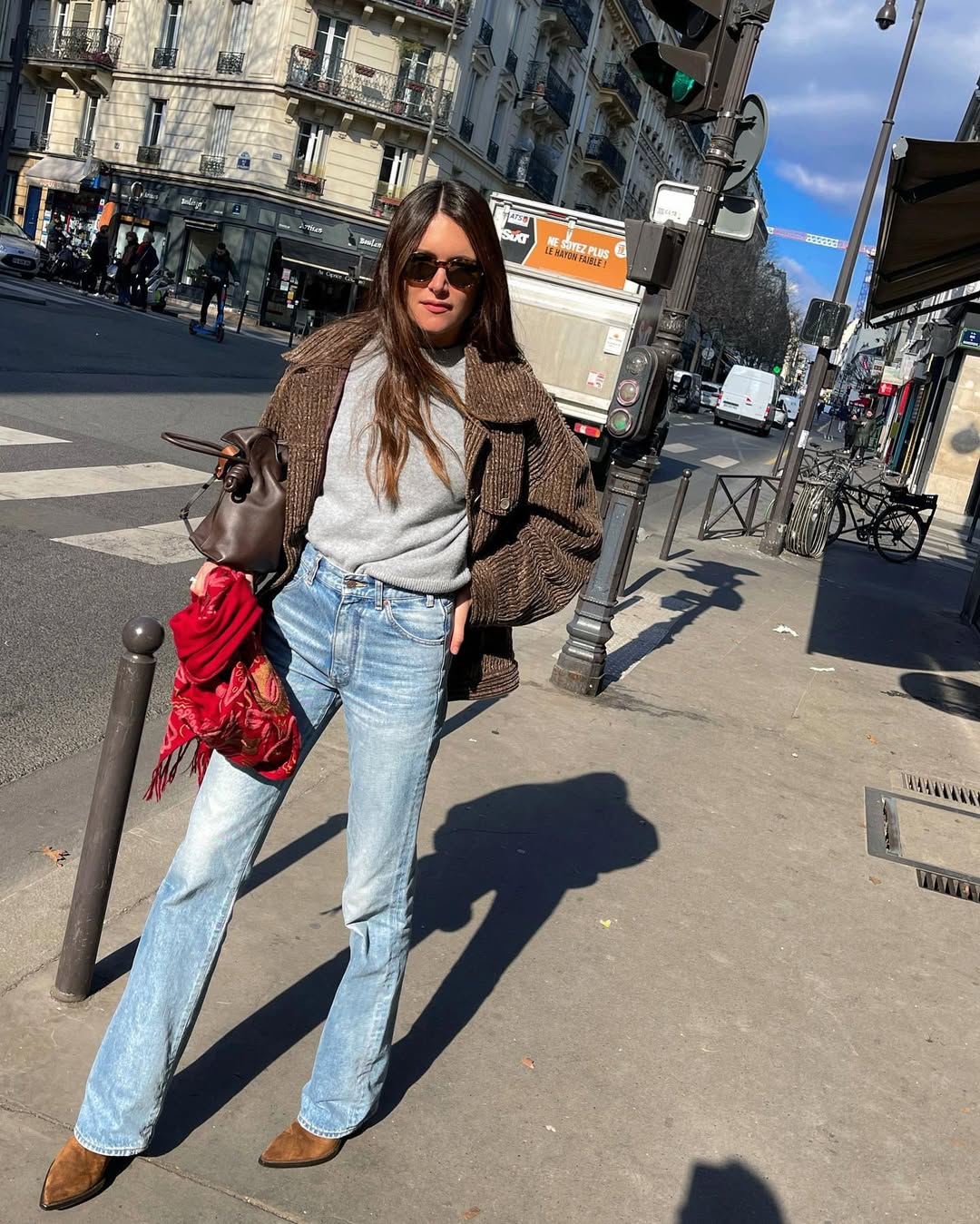 woman wearing slim-flare jeans with grey sweater and red bag