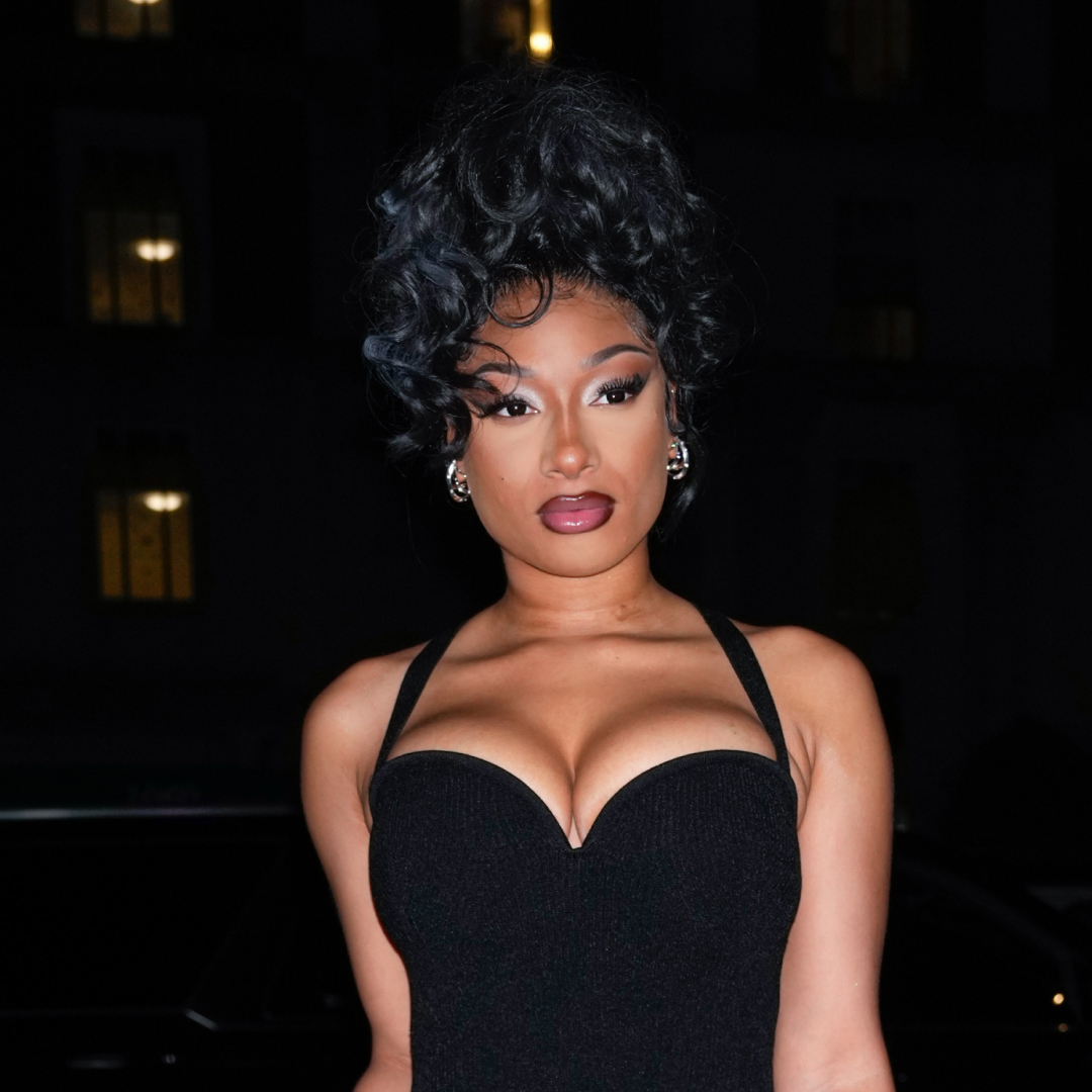 Megan Thee Stallion wearing a black dress and curly updo hairstyle. 