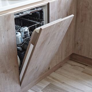 Built-in dishwasher with open door under white granite top