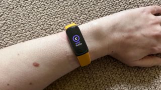 A Fitbit Inspire 3 on a person's wrist, showing sleep time