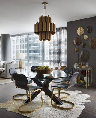 A dining room with dark grey walls and gold elements