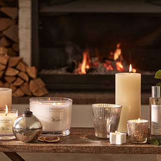 Winter candle on a table infront of an open fire