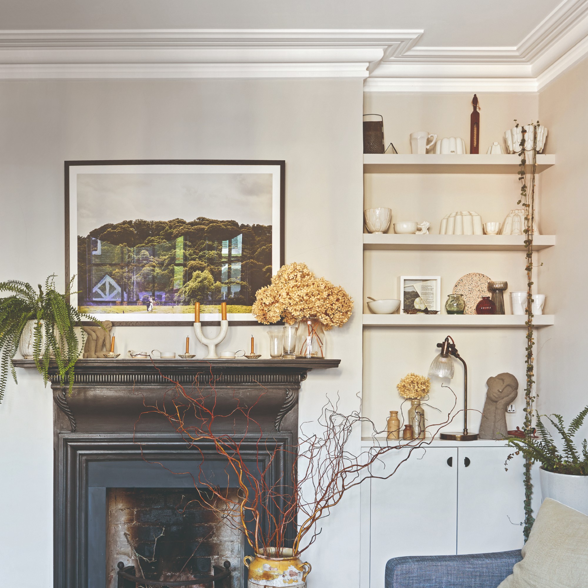 A living room with shelves built into an alcove displaying decorative objects and a vintage-style aged brass and glass lamp