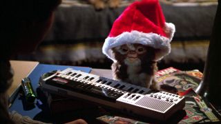 Gizmo (voiced by Howie Mandell) sits behind a keyboard while wearing a Santa hat in Gremlins