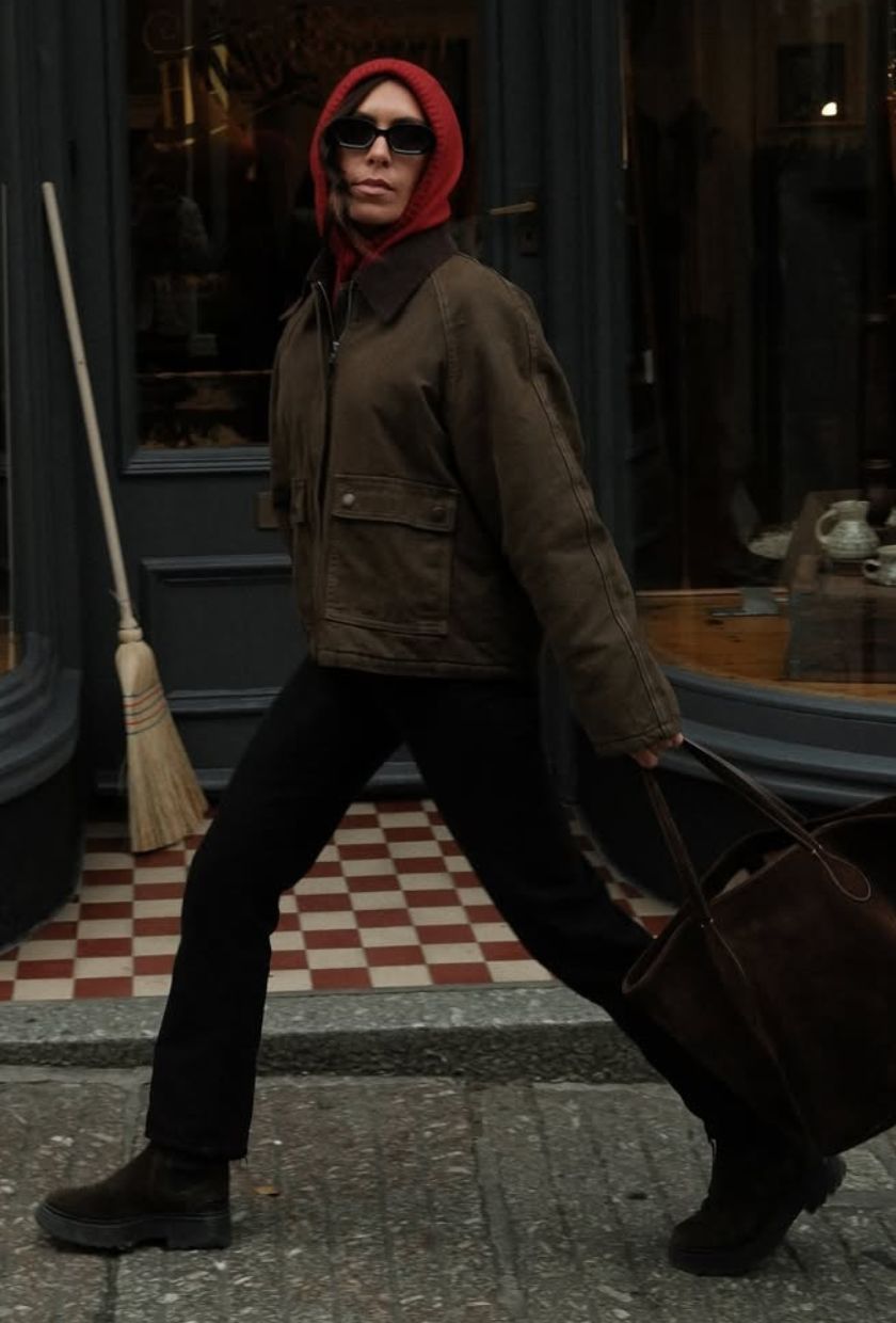 @_jessicaskye wears a khaki canvas coat, black jeans. brown boots, suede tote and a red knitted hood