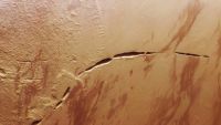 A satellite photo of mars with a massive, curved crack in its surface