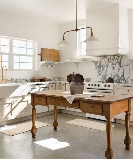 An :-shaped neutral kitchen with cabinets painted in Alabaster by Sherwin-Williams, paired with marble countertops and a wooden freestanding island