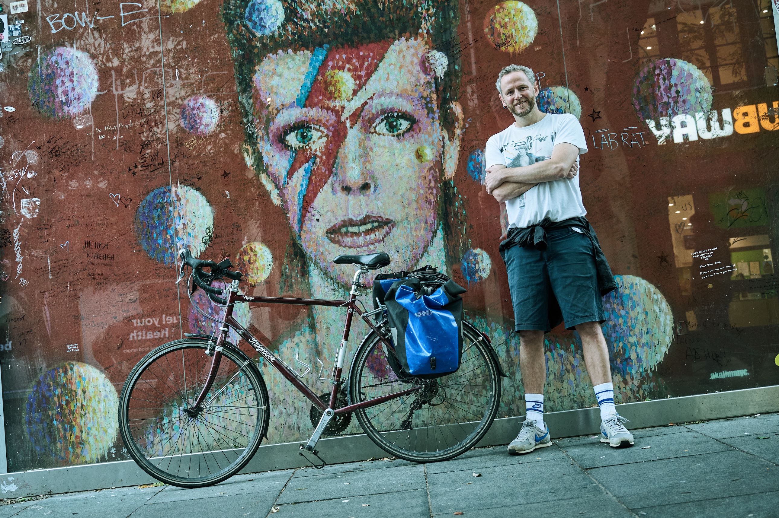 James Briggs standing next to a David Bowie mural in London
