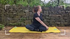 Samantha Priestley stretching in yoga routine, sitting on mat in backyard, part of doing yoga every day