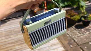 the roberts rambler bt stereo dab radio being held by its carrying handle