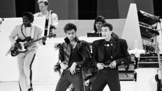 George Michael and Andrew Ridgeley of pop duo Wham! with Deon Estus behind on bass, at their farewell concert entitled The Final. Wembley Stadium, 28th June 1986.