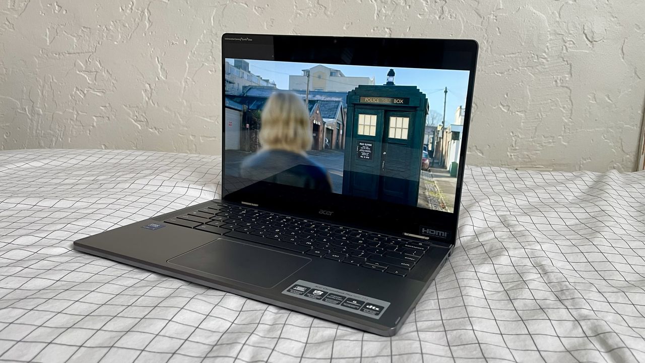 An angled view of an open and powered on laptop on top of white fabric with a grid pattern.