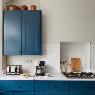 Blue kitchen units with copper saucepans and white metro tiles