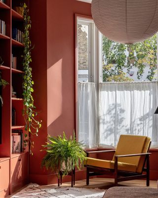 Red living room with yellow accent chair and two green plants