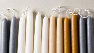 A row of candle sticks in a range of colours from white to gray