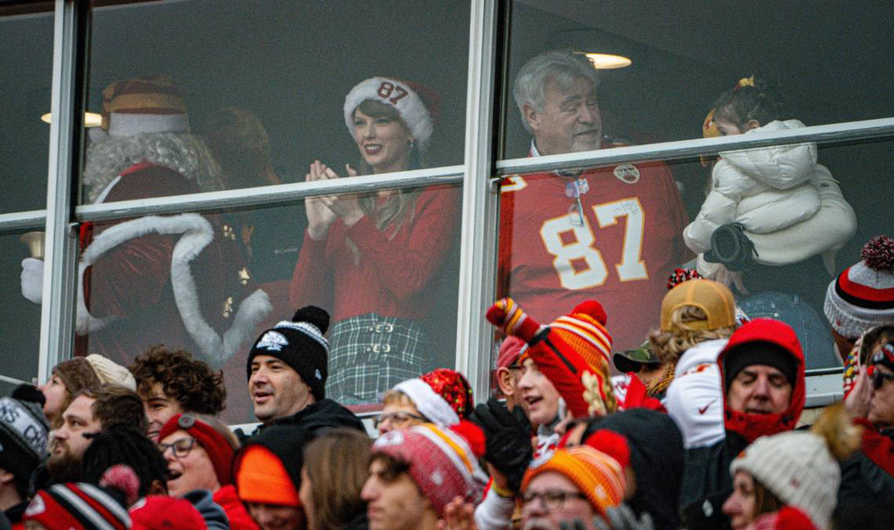 Taylor Swift at a Kansas City Chiefs christmas game wearing a red sweater and plaid skirt