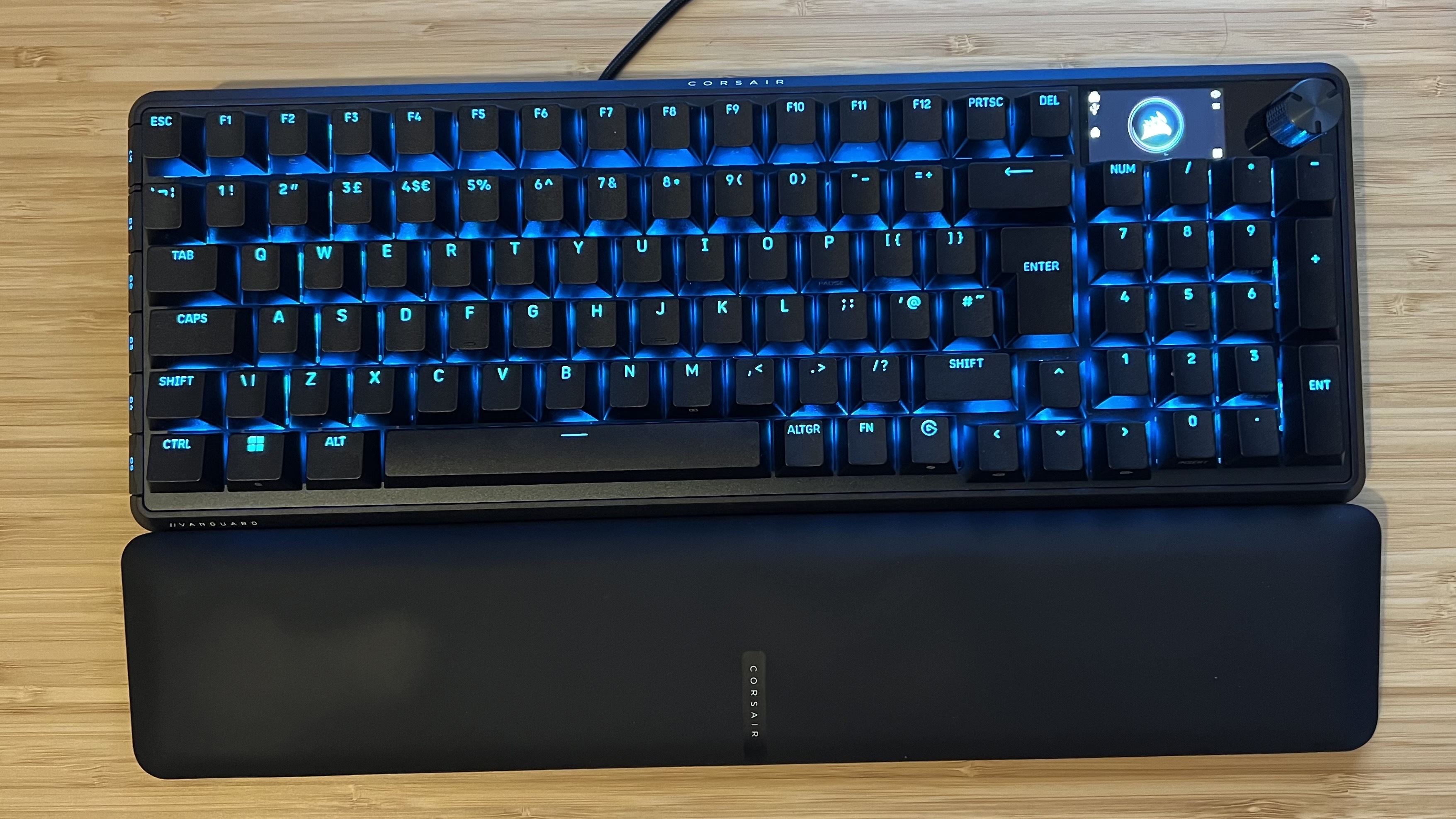 Corsair Vanguard Pro 96 gaming keyboard with wrist rest on a wooden desk