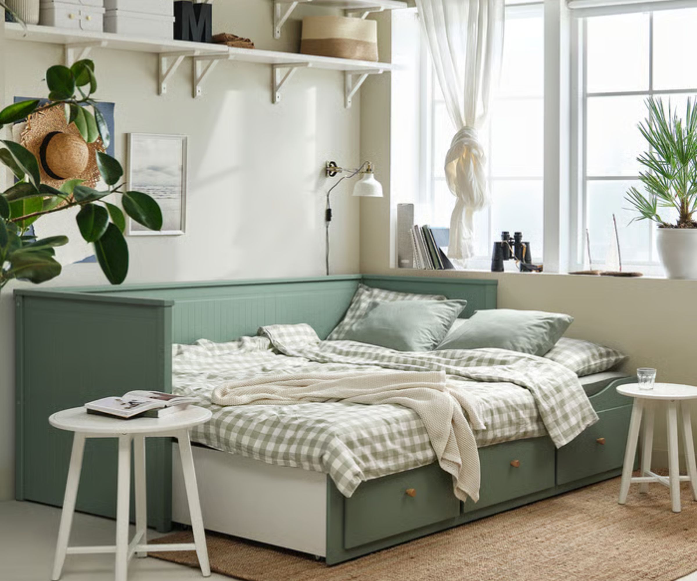IKEA HEMNES bed in sage green with gingham bedding, with a jute rug, white wooden side tables, and white shelves above with baskets and storage boxes.