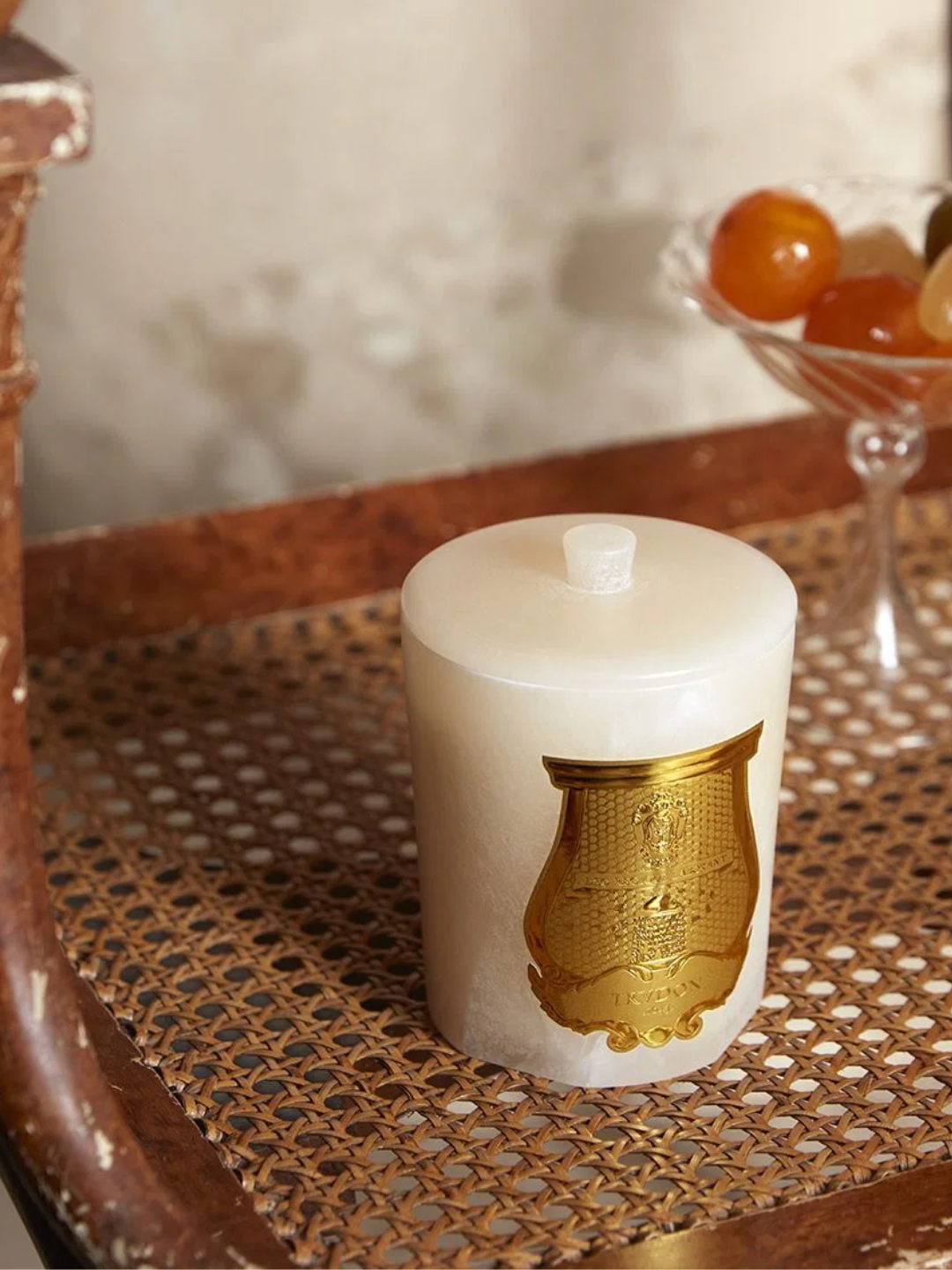 A scented candle with a stone lid from Trudon on a woven seat