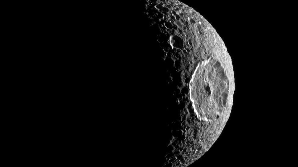 A black and white view of a moon shrouded in darkness.