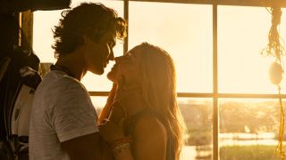 (L to R) Chase Stokes as John B, Madelyn Cline as Sarah Cameron almost kissing while being backlit by the sun.